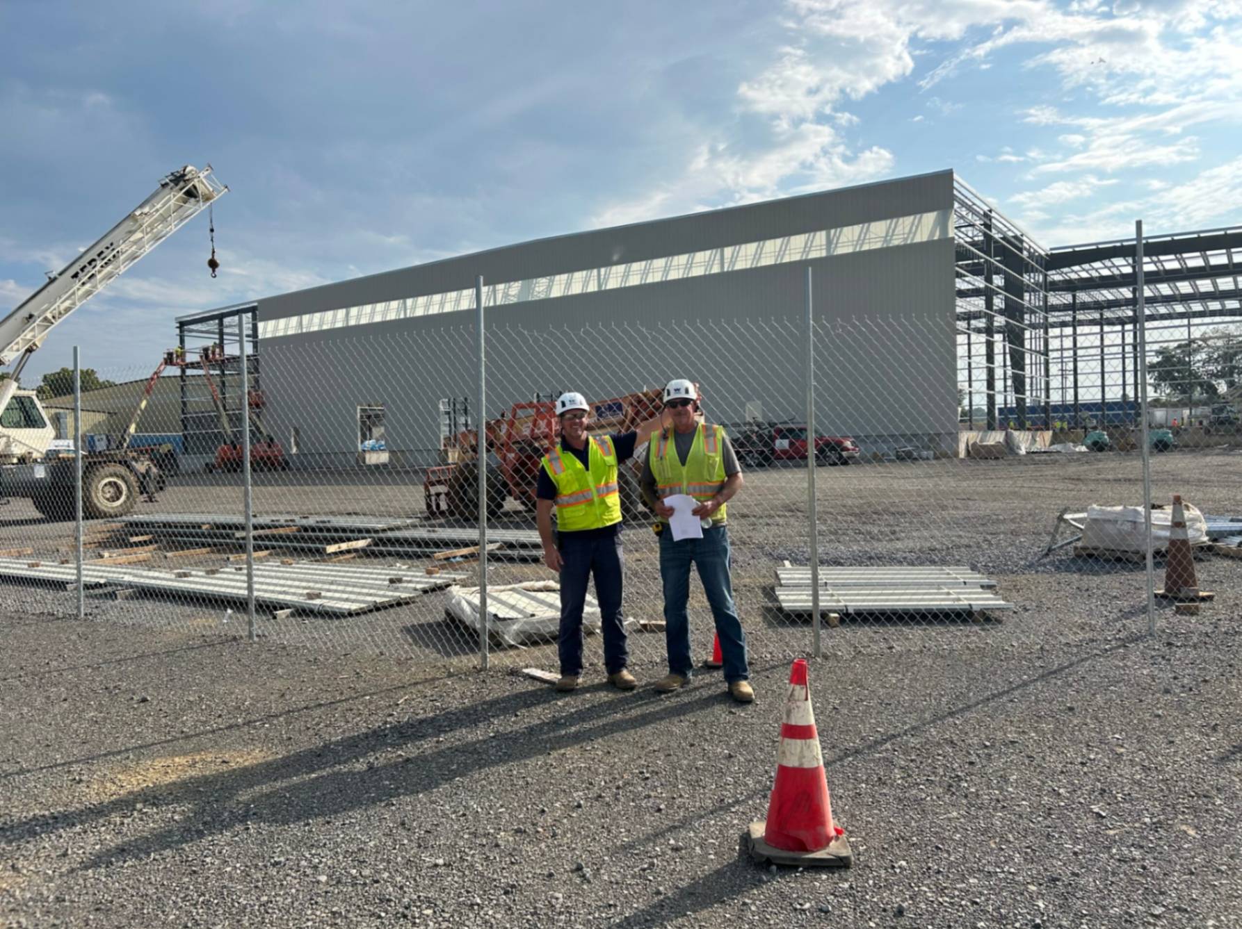 Warner Construction workers posting together by a chain-link fence